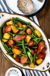 green beans and potatoes casserole with sausage on wooden board