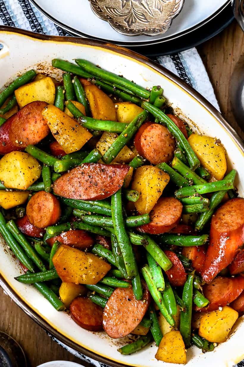 green beans and potatoes casserole with sausage in white baking dish