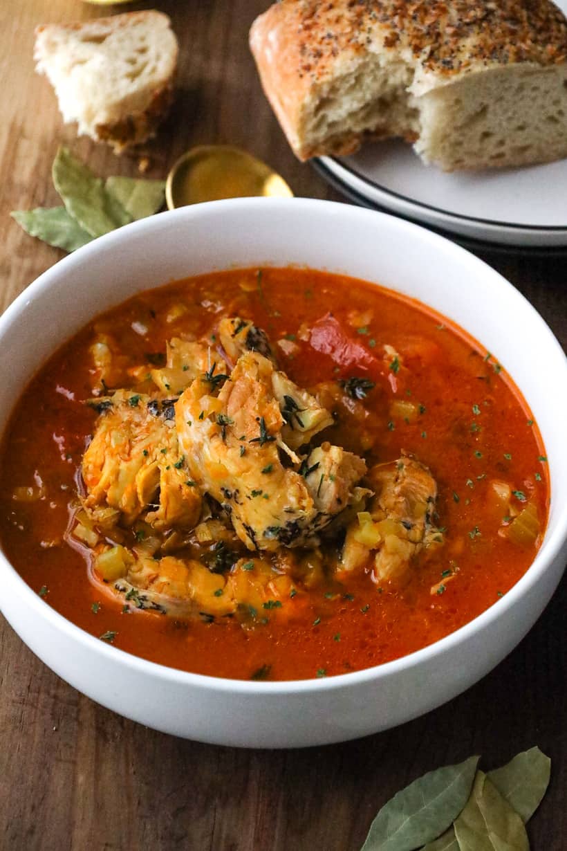 bouillabaisse topped with herbs in white bowl