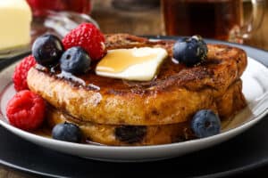 syrup, butter, and fruits on top of brioche French toast