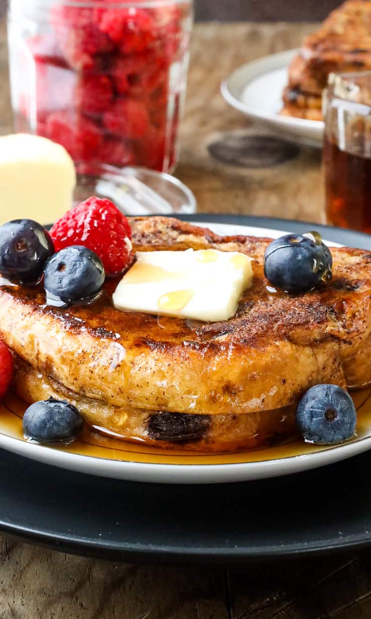 French toast on white plate with fruits and butter