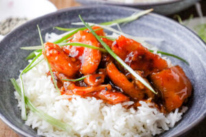 rice topped with firecracker chicken and green onions