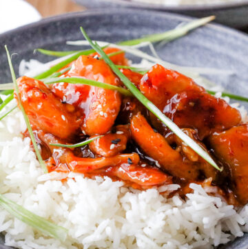 rice topped with firecracker chicken and green onions