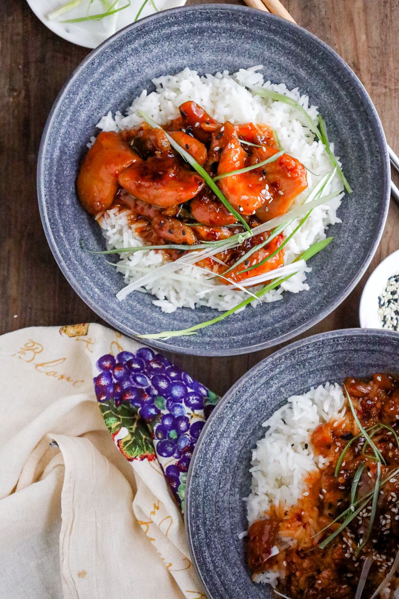 White rice topped with firecracker chicken and green onion strips.