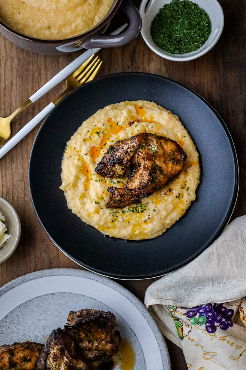 Fish and grits on black plate with