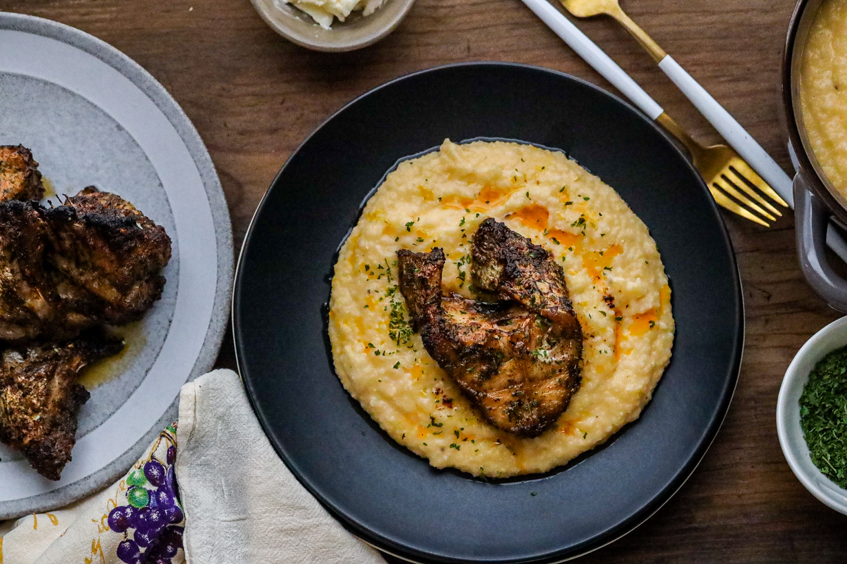 Fish and Grits on black plate on wooden board