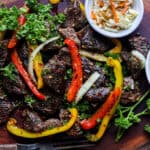 Steak bites on wooden board with herbs and peppers