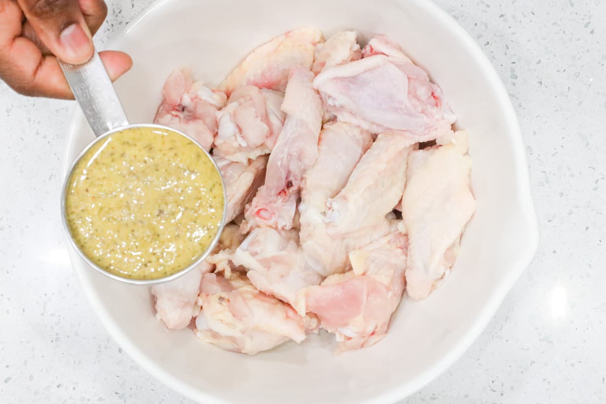 hand pouring seasoning to chicken