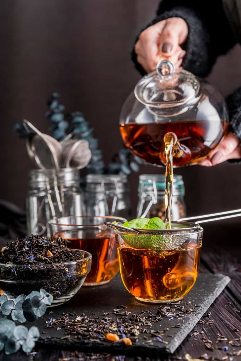 hand pouring tea in a tea cup