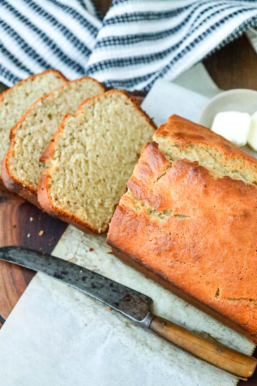 Moist banana bread on wooden board with knife.