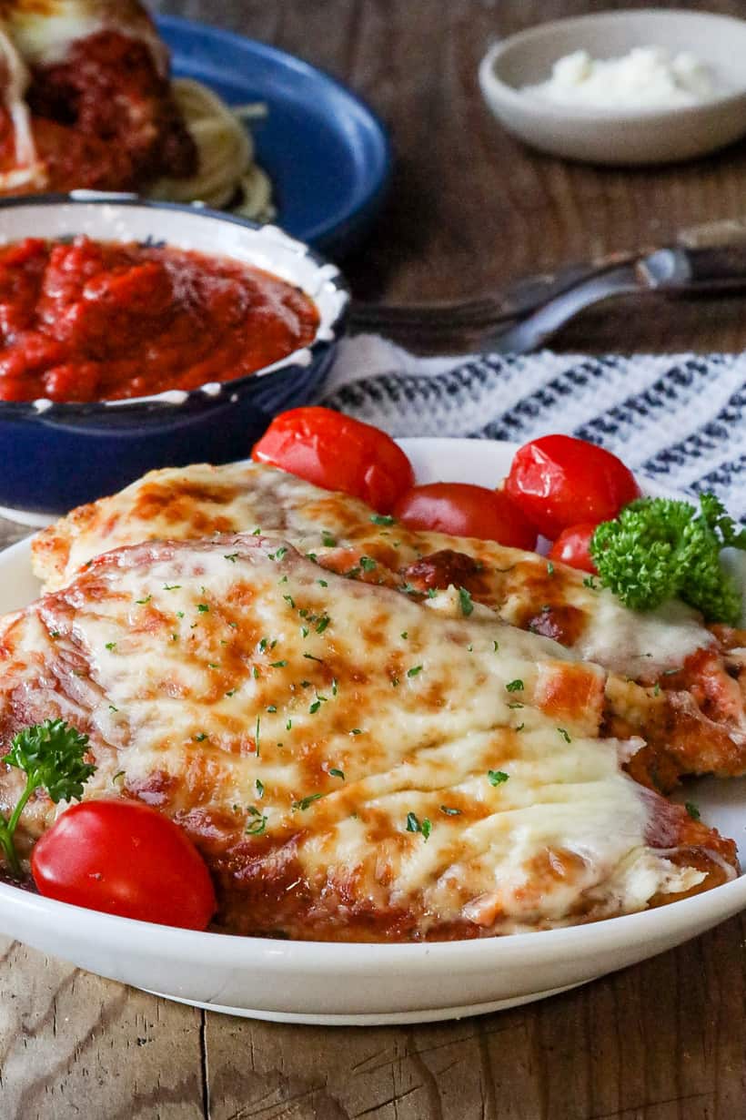 parmesan chicken with tomatoes on white plate