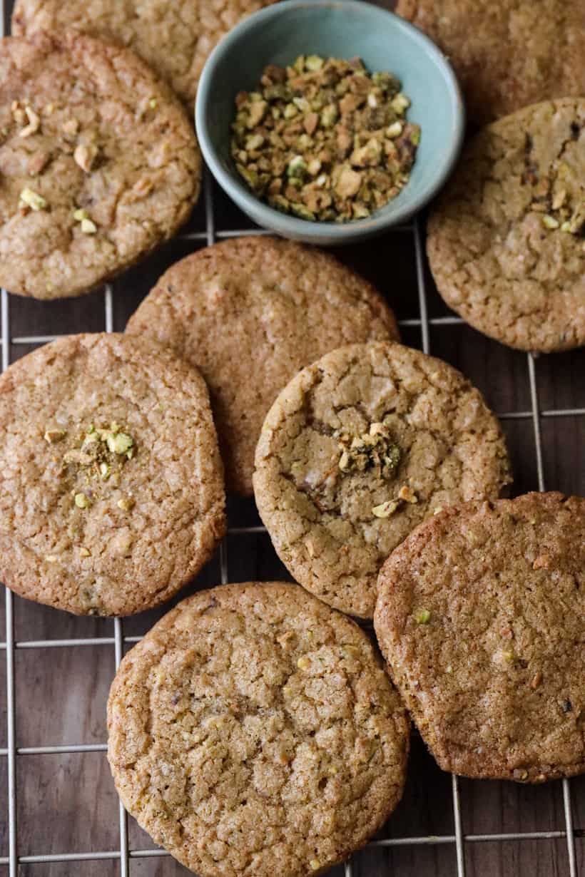 pistachio cookies with crumbs on cooling rack