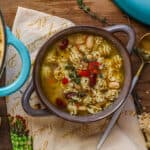 Vegan minestrone soup in brown bowl on wooden board