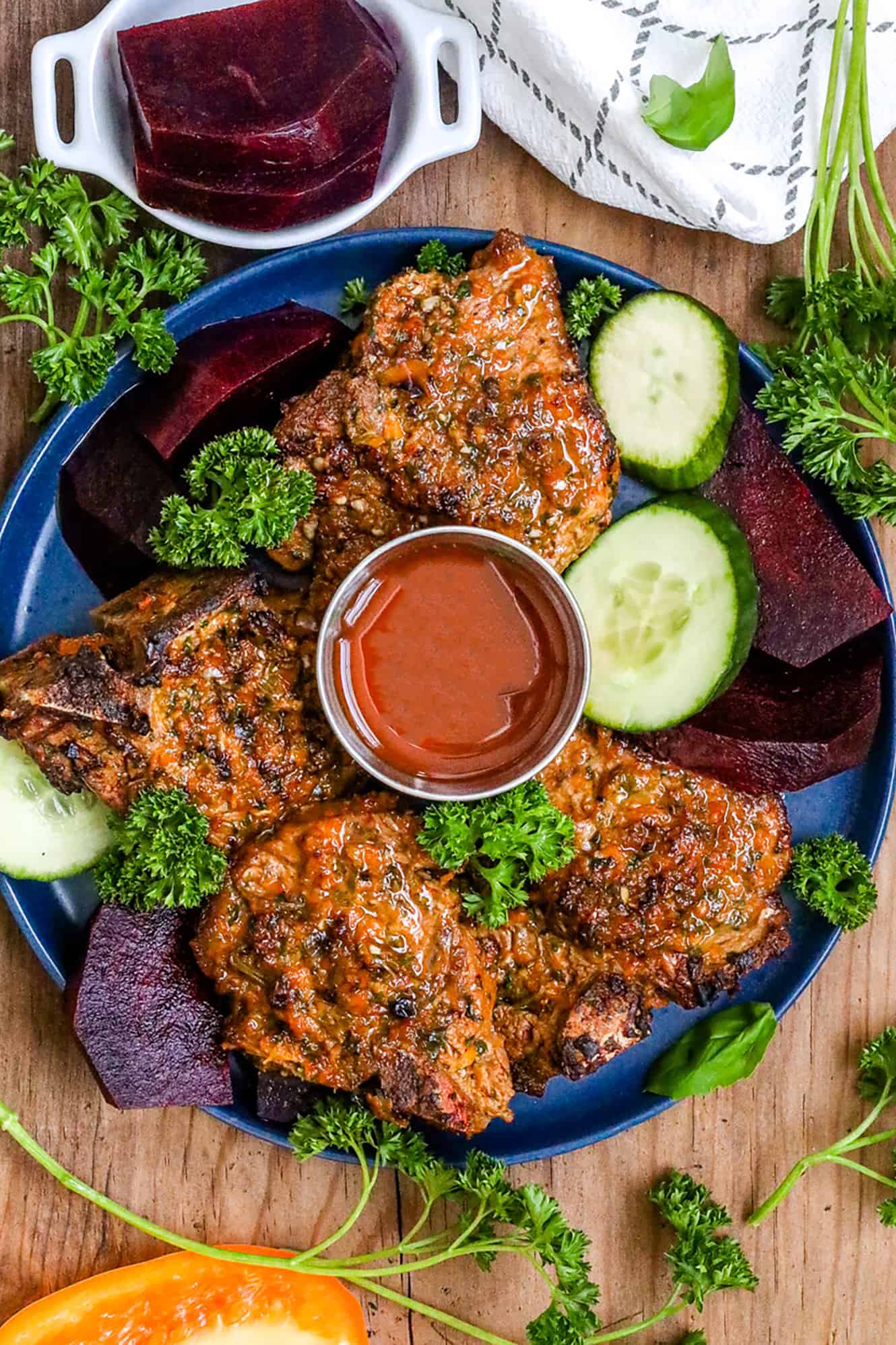 Cooked lamb chops on blue plate with beets and cucumbers