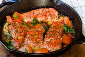 honey mustard salmon with parsley and tomatoes in skillet