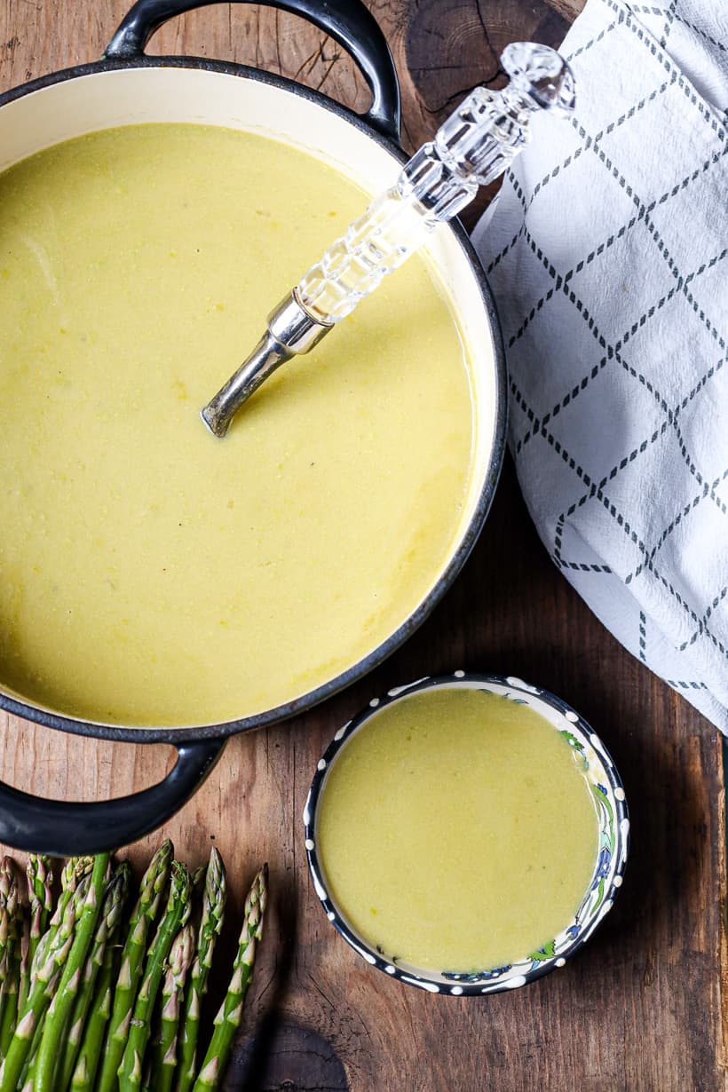 Soup in saucepan with spoon and asparagus on the side