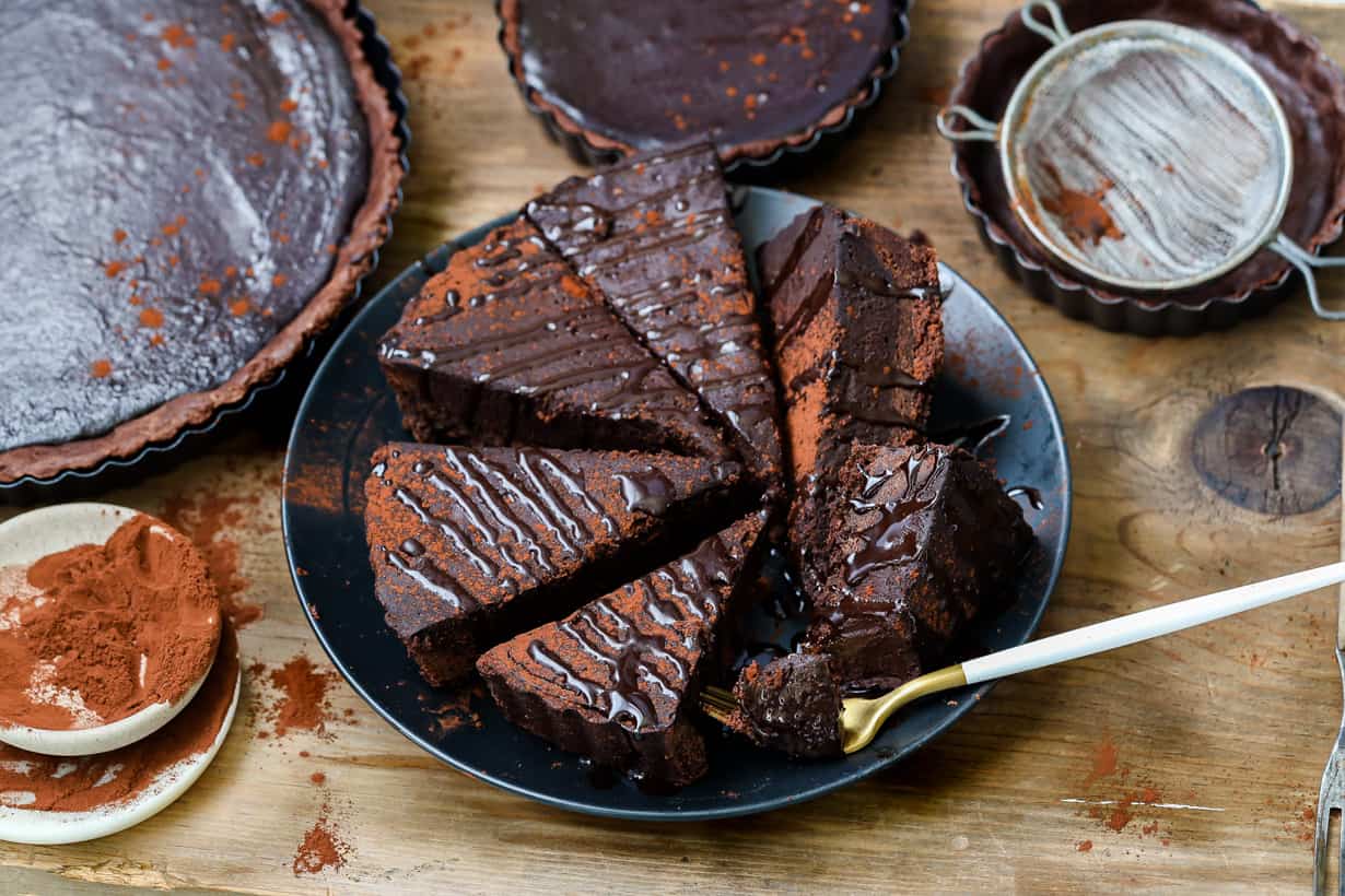 French chocolate tart on topped with melted chocolate on black plate