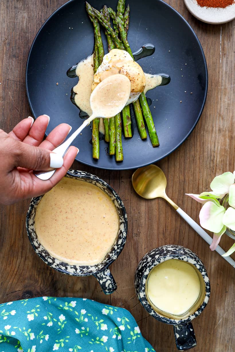 hand pour hollandaise sauce over eggs