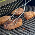tong with steak on grill