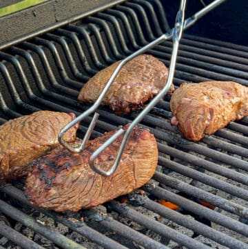 tong with steak on grill
