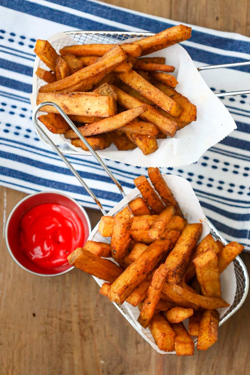 yam fries in baskets on wooden board with ketchup
