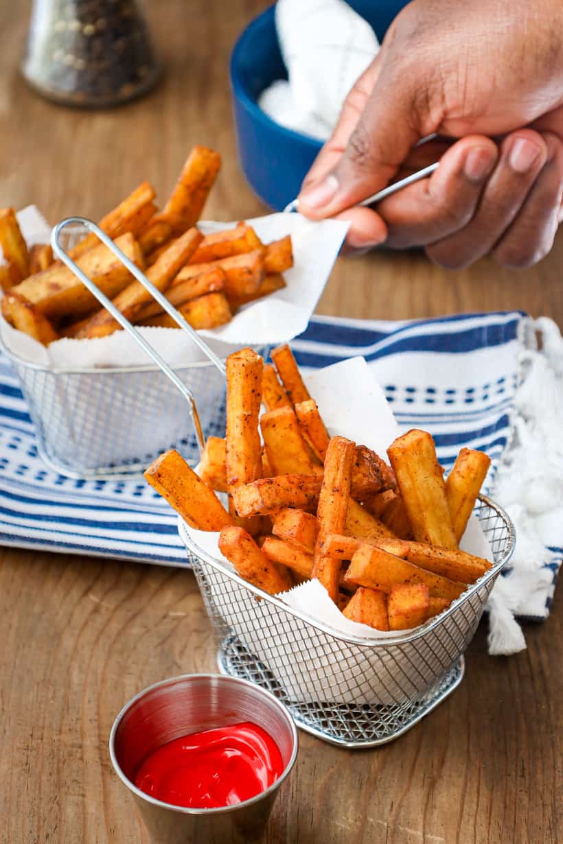 hand holding yam fries basket on wooden board