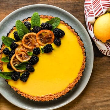 Tart dessert topped with fruits and mint on plate