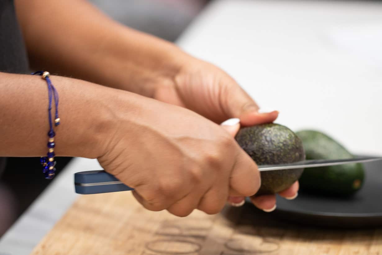 hand holding knife to cut avocado