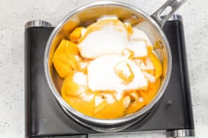 Mango and sugar in saucepan