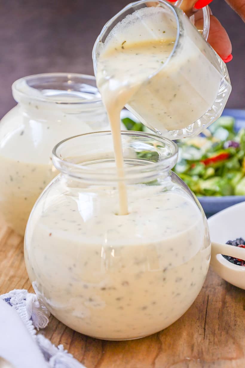 hand pouring tahini dressing