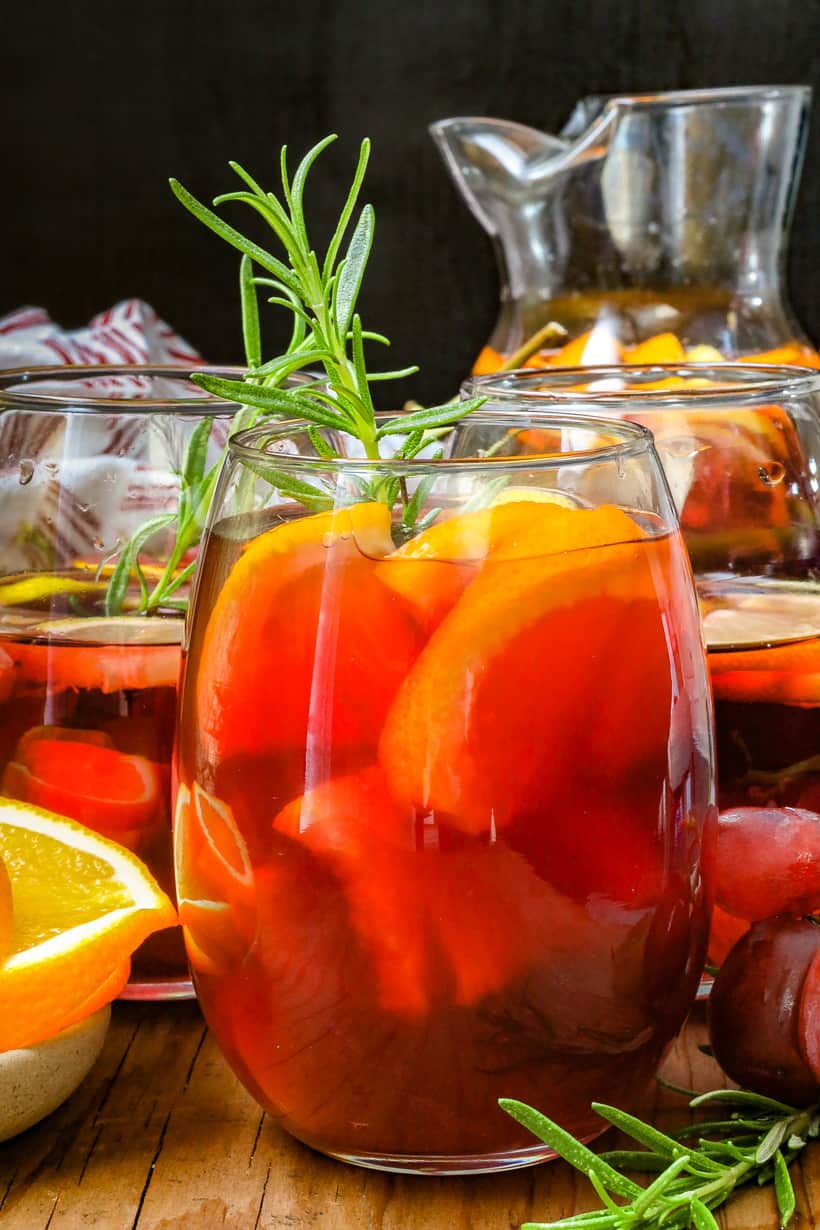 sangria with herbs in glass and pitcher in the back