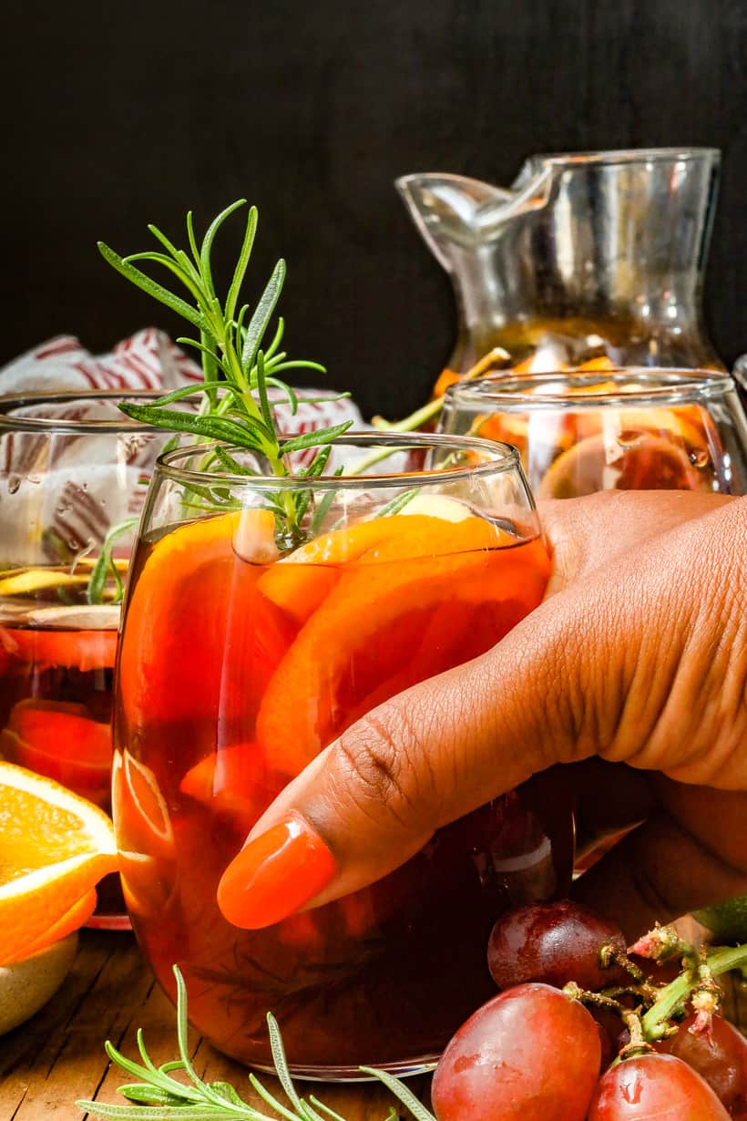 hand holding non-alcoholic sangria with pitcher in the back