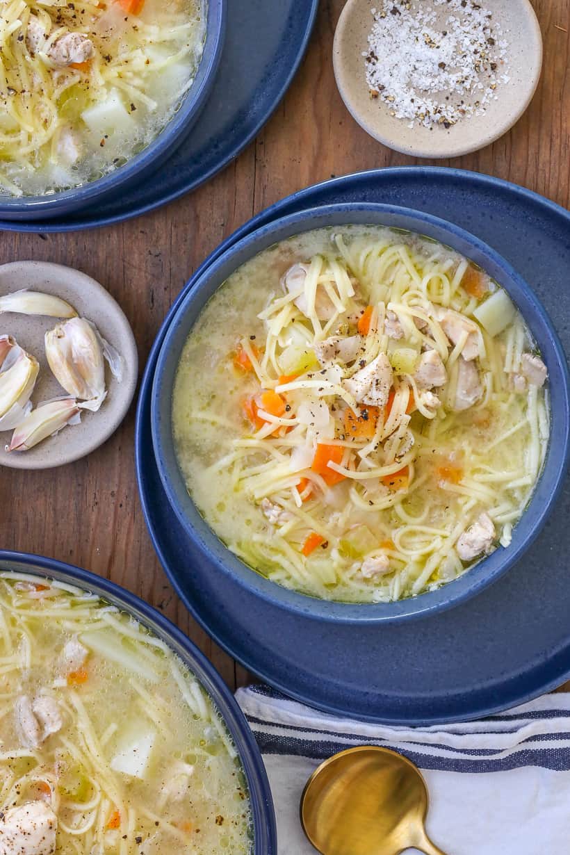 chicken broth soup in 3 bowls on wooden board