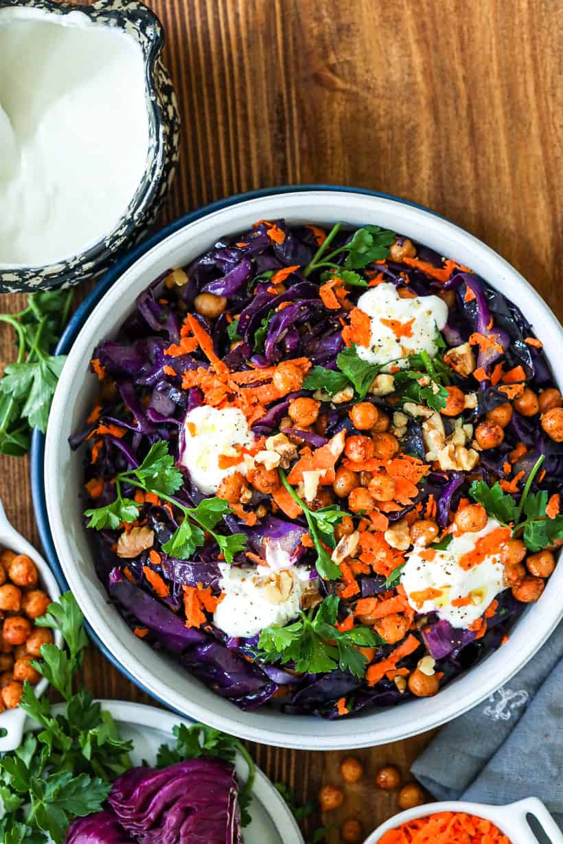 red cabbage salad in bowl topped with parsley and yogurt