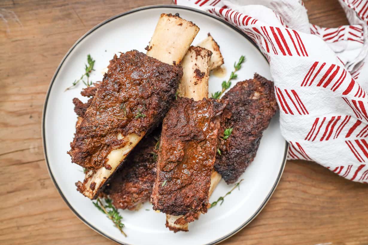 jerk ribs on white plate with herbs and dish towel