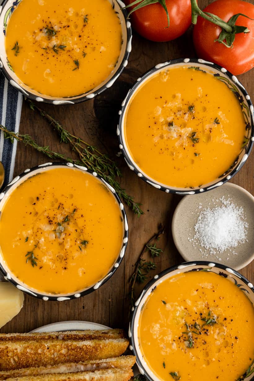 four bowls of tomato bisque and grilled cheese sandwich