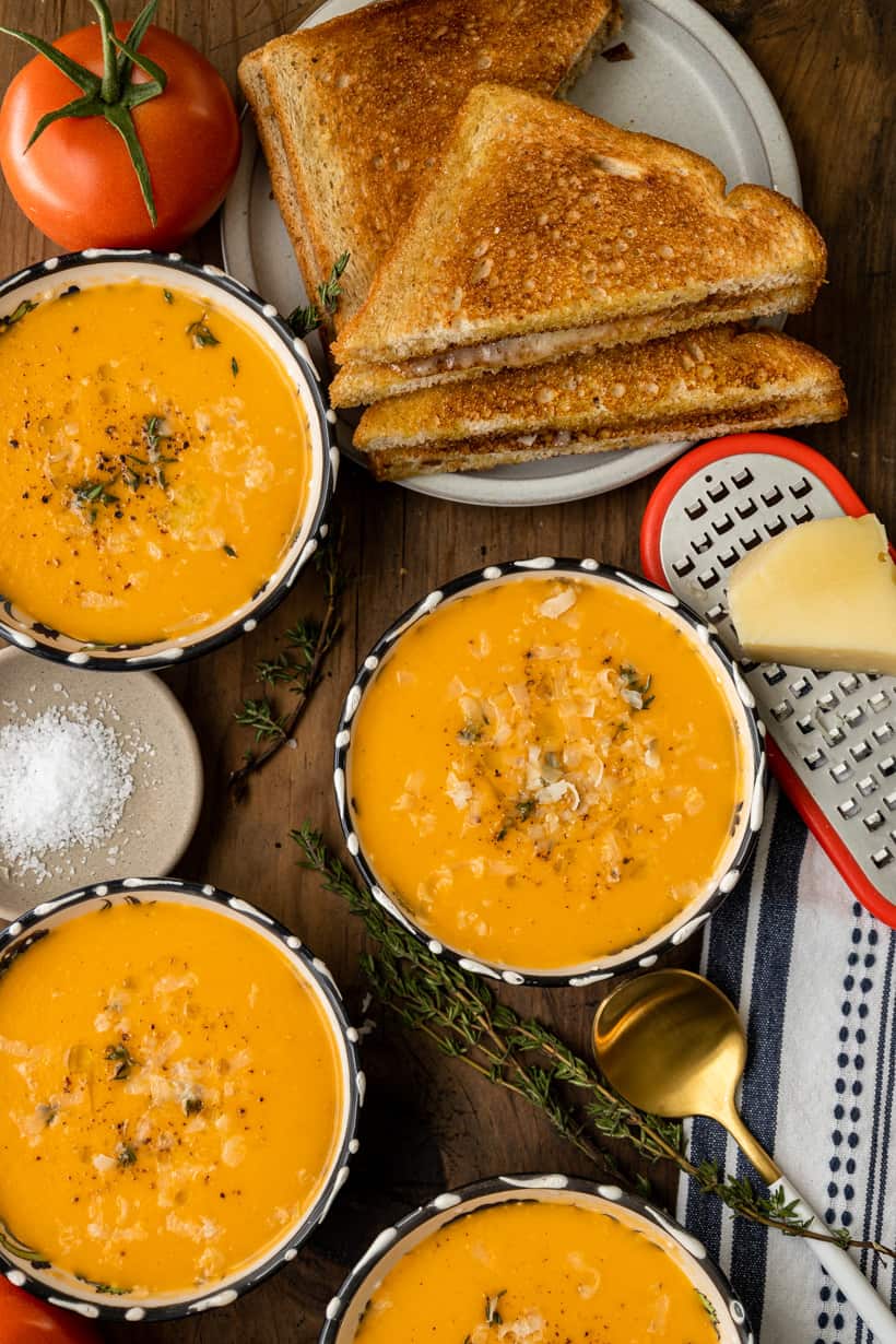 four bowls of tomato bisque and grilled cheese sandwich