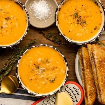 tomato bisque with grilled cheese and herbs on board