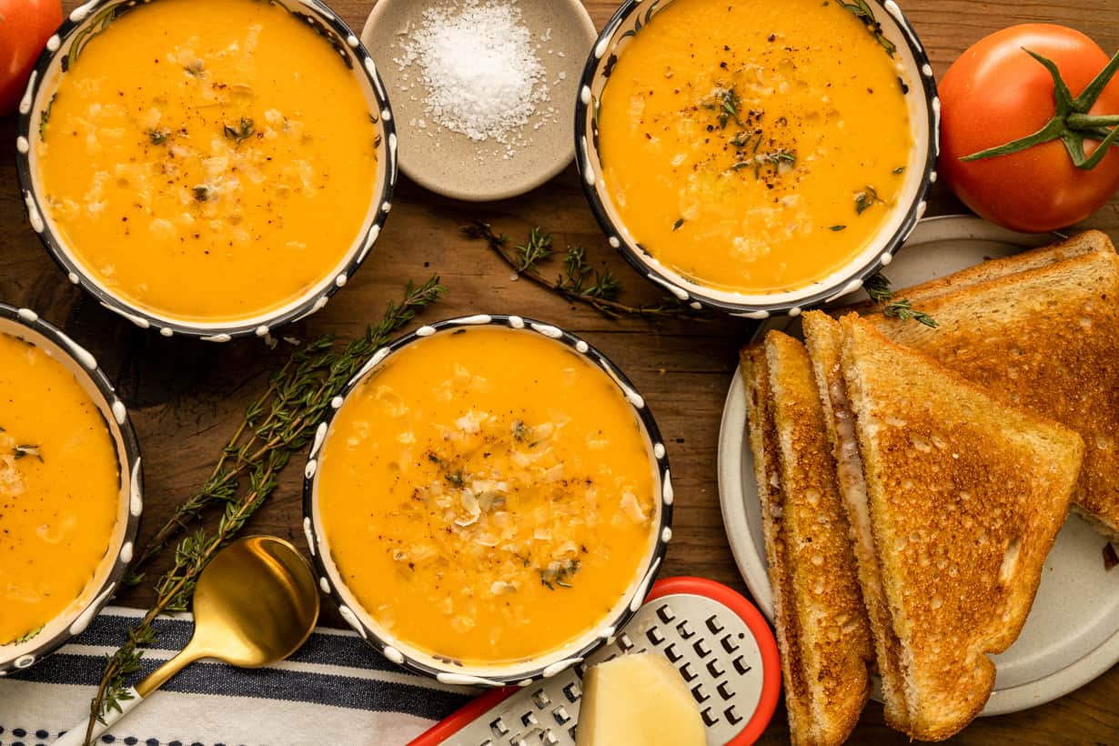 tomato bisque with grilled cheese and herbs on board