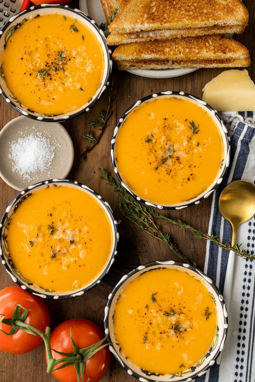 four bowls of tomato bisque and grilled cheese sandwich