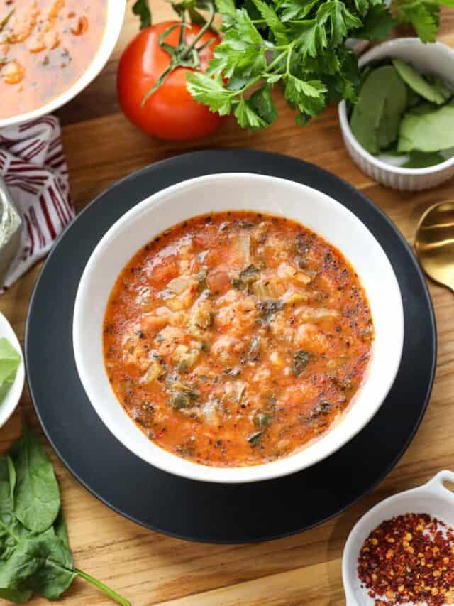 Bread Soup (Soup pen) in white bowl with herbs and tomato on board