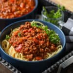 spaghetti bolognese in blue bowl on black tray