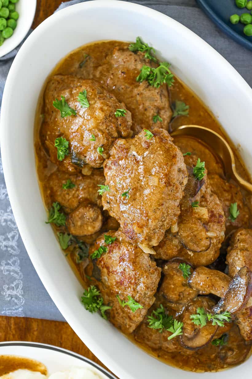 Salisbury steak in white bowl topped with parsley