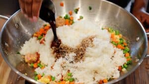 Pouring soy sauce over rice and vegetables