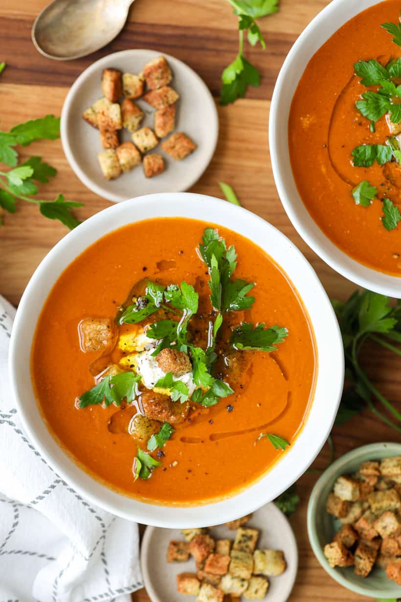 tomato basil bisque in two bowls with croups and garnished with fresh parsley
