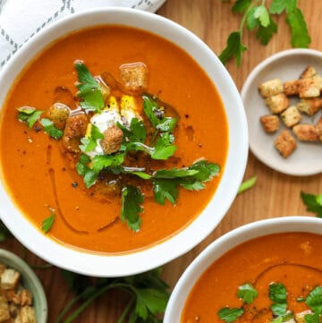 tomato basil bisque in two bowls with croups and garnished with fresh parsley
