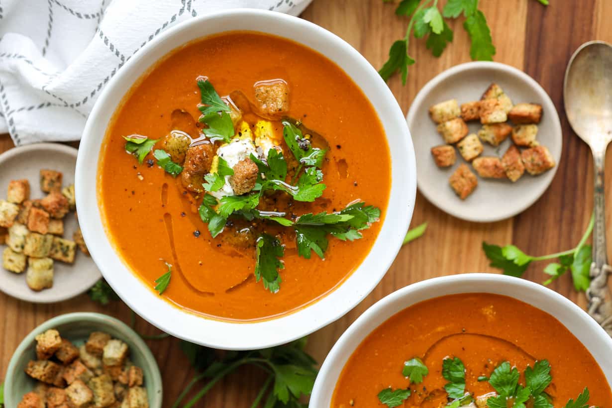 tomato basil bisque in two bowls with croups and garnished with fresh parsley