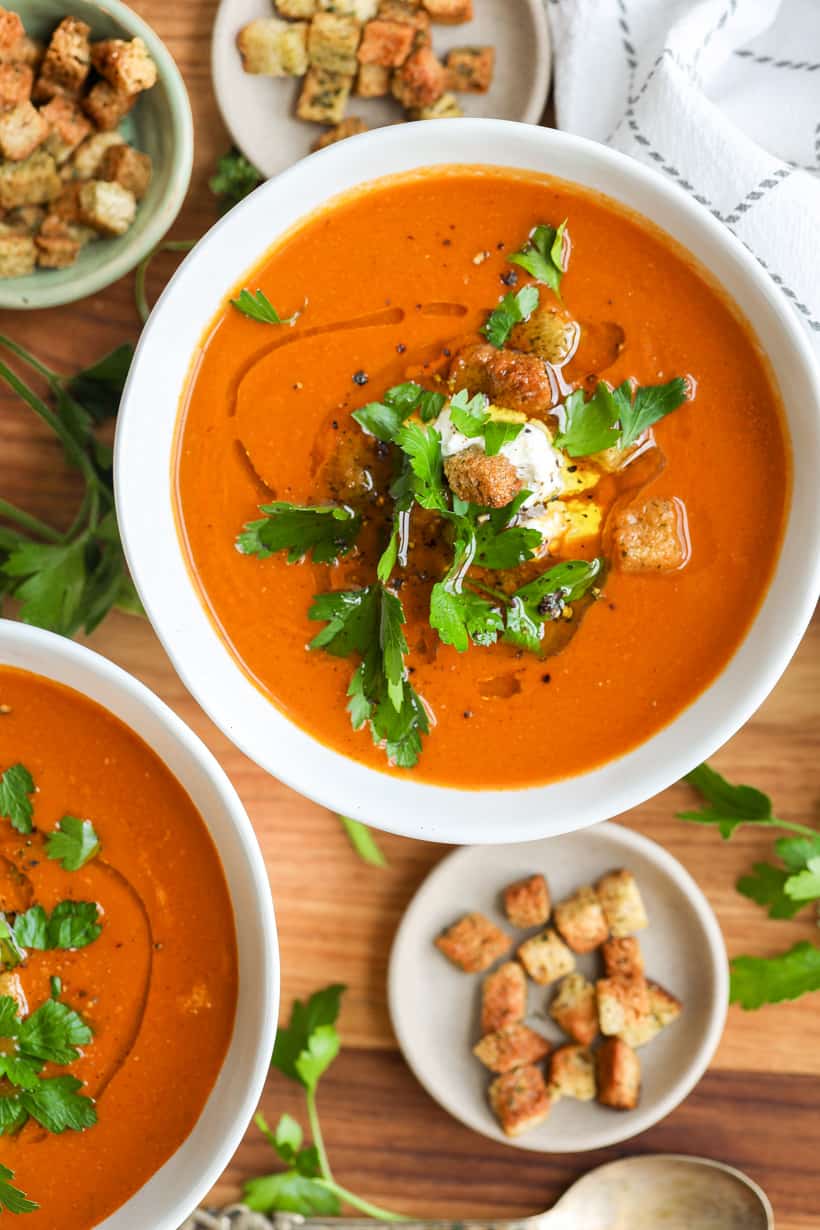 tomato basil bisque in two bowls with croups and garnished with fresh parsley