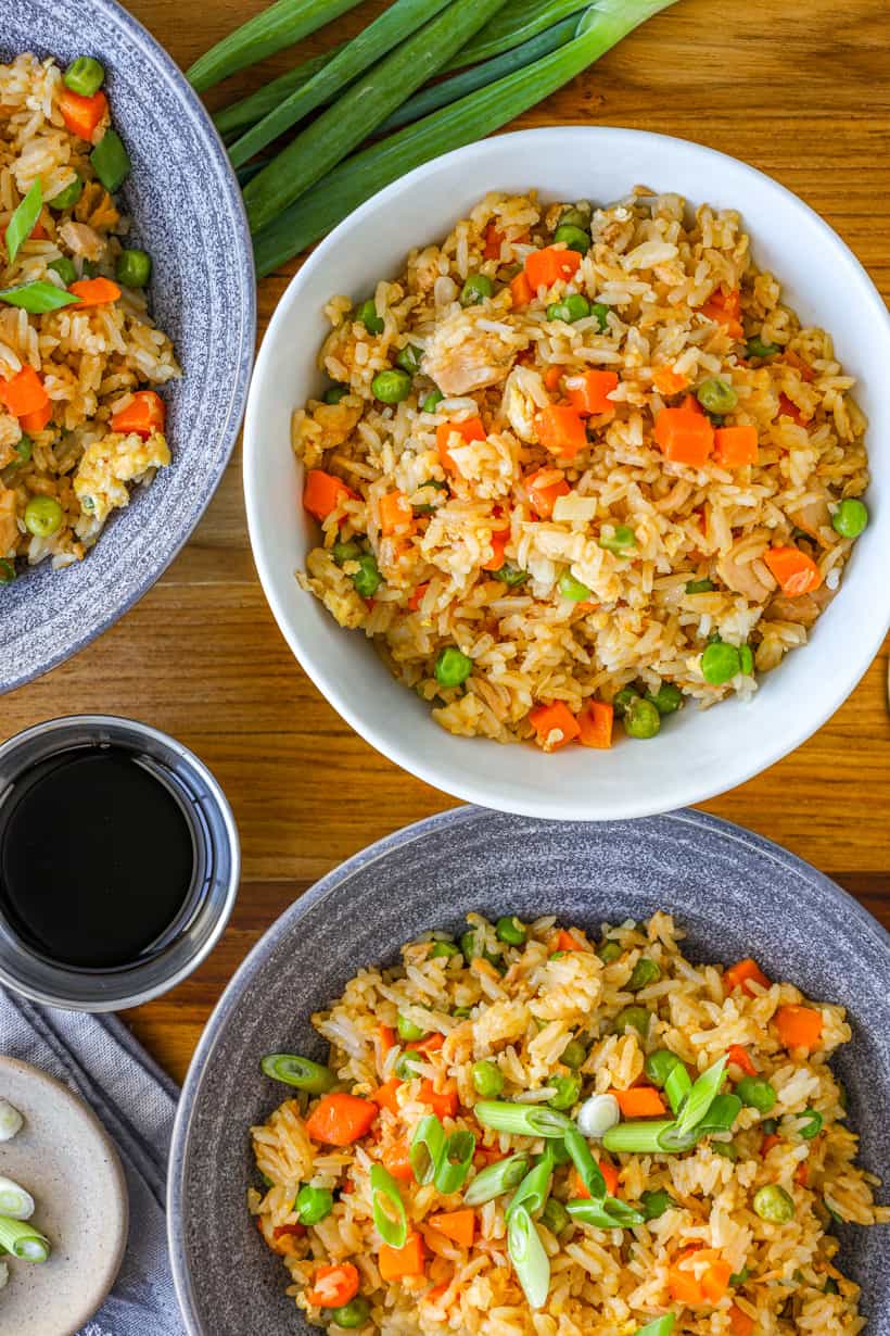 tuna fried rice in bowls on a wooden board and fresh green onions on the side.