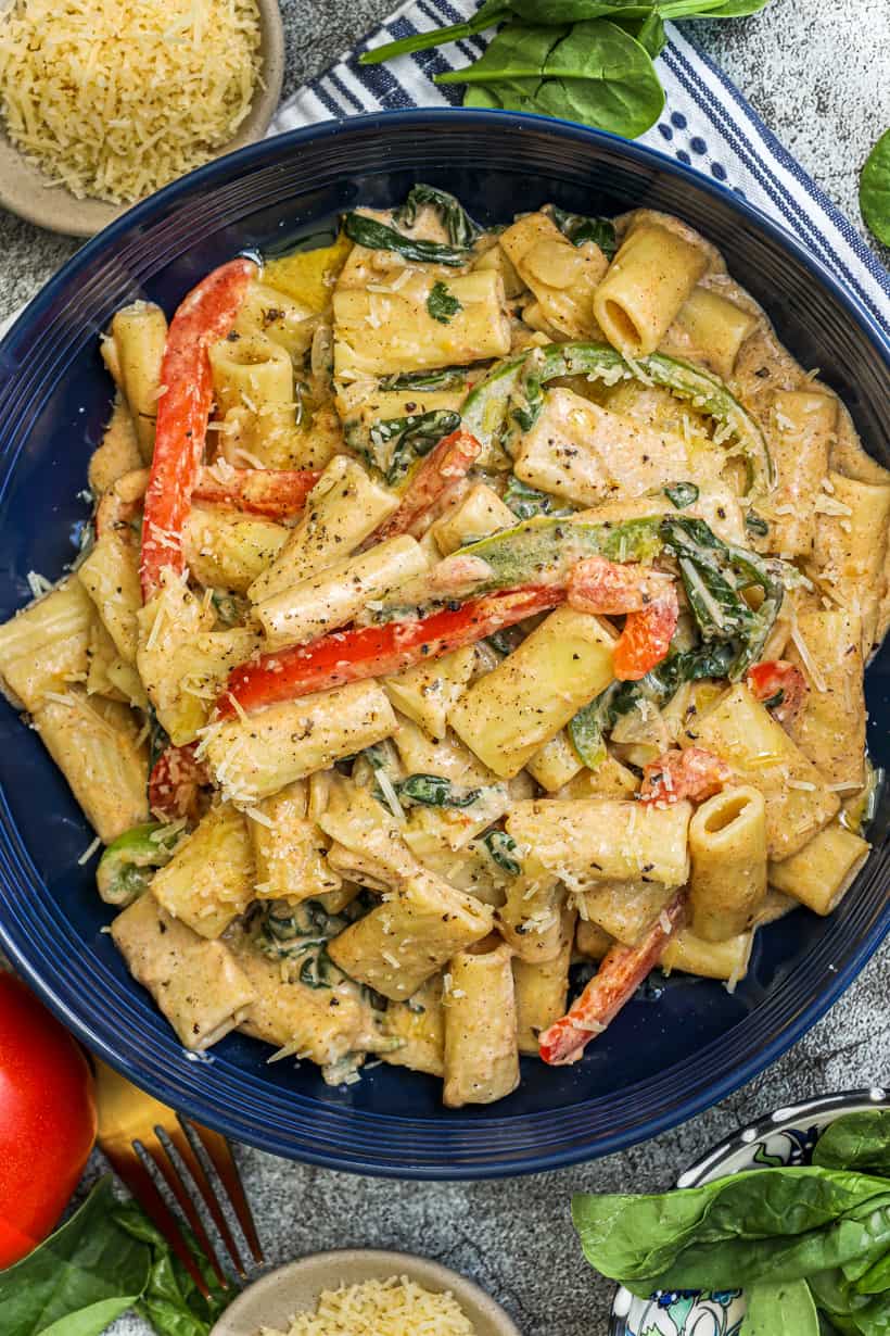 Rasta pasta in a blue bowl topped with fresh cracked peppers